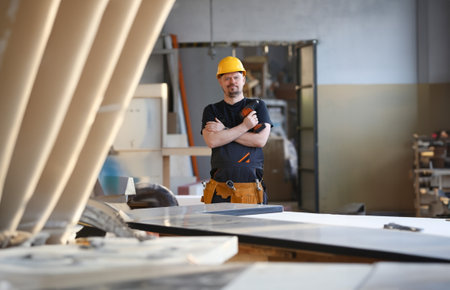 Arms of worker using electric drill closeup