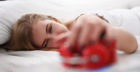 Young beautiful woman waking up in the morning alarmの写真素材