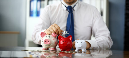 Funny businessman listen three piggybanks for cashの写真素材