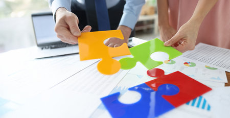 Office workers put together bright jigsaw elementsの写真素材