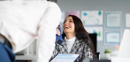 Businesswoman flirting with corporate male worker touching his tie and laughingの写真素材