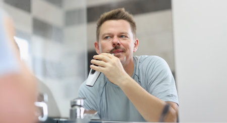 Middle aged man shaving beard with electronic machineの写真素材