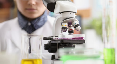 Woman scientist explore purple sample under microscope in laboratoryの写真素材