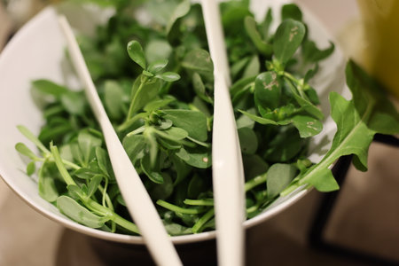 A selection of Fresh Salad Greens Complete with Colorful Serving Utensils for Enjoymentの写真素材