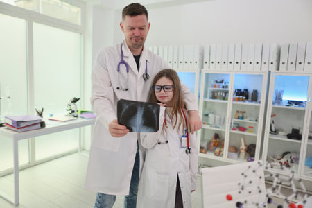 A Doctor and their Young Assistant are Engaged in a Collaborative Examination of an Xray Togetherの写真素材