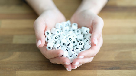 Holding letter cubes in delicate hands to spark creativity and playful word formation in a warm...