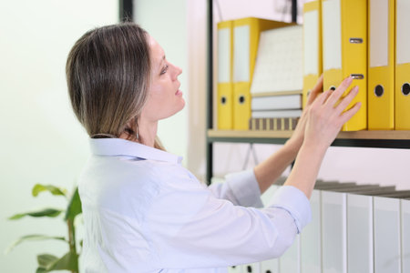 Organizing files with care in a bright office space filled with greenery and vibrant yellow binders