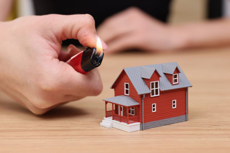 Lighting a miniature house on fire during a creative art project in a cozy workspace