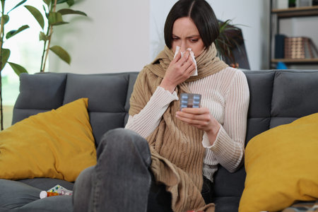 Woman in a cozy living room dealing with a cold while wrapped in a blanket, surrounded by comfort