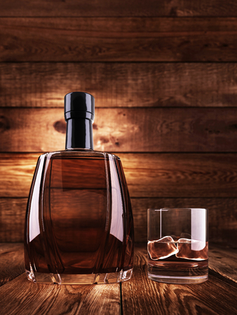 A bottle of cognac with a glass of ice. On a wooden table. Background wood planks. 3D render.の写真素材