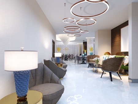 A modern reception area with large upholstered designer armchairs and a large chandelier of golden rings. Side tables with lamps and elegant vases. White self-leveling floor. 3d rendering.の写真素材