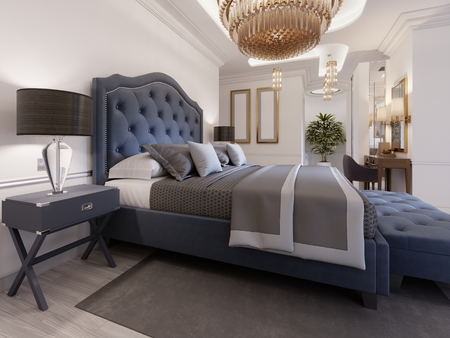 A luxurious bedroom in a classic style with gold elements and a blue bed cloth and a wooden dresser and dressing table. 3d rendering.の写真素材
