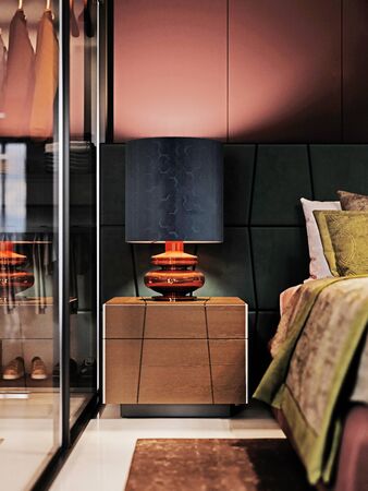 Fashionable bedside table with the lamp on next to the bed, evening light. Front view. 3D rendering.の写真素材