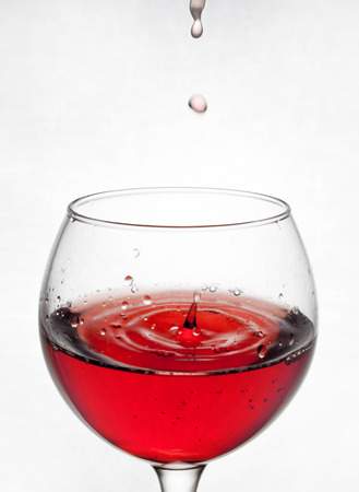 glass goblet on white background with liquid splashingの写真素材