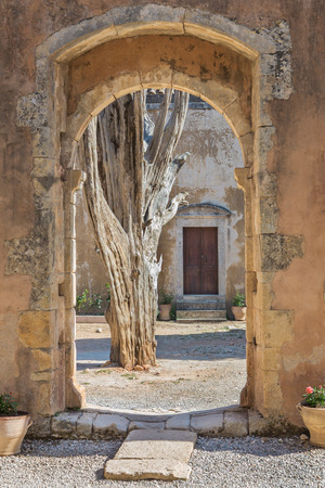 The old tree in the Arkadi Monastery, Crete, Greece (view through arch)の写真素材