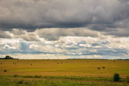 A cloudy overcast sky over a field of hay balesの写真素材
