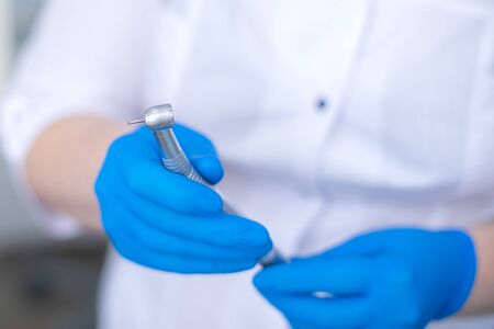 hand in blue rubber glove holds dental burの写真素材