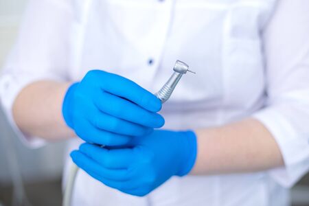 hand in blue rubber glove holds dental burの写真素材