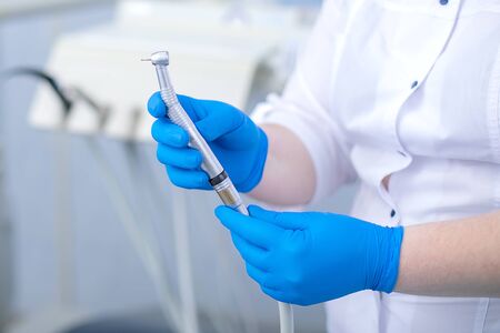 hand in blue rubber glove holds dental burの写真素材