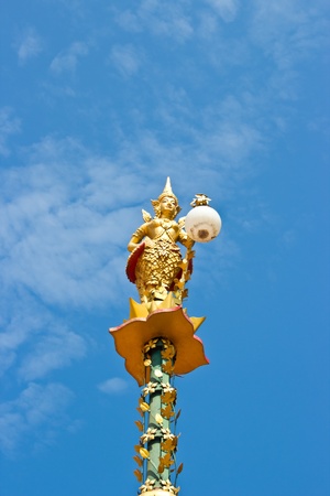 Golden light poles with traditional Thai angle sculpture in the park の写真素材