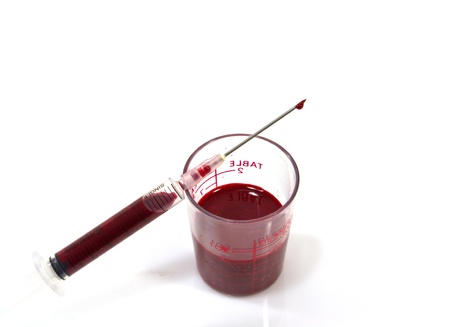 Needle of syringe with blood drop. Isolated over whiteの写真素材