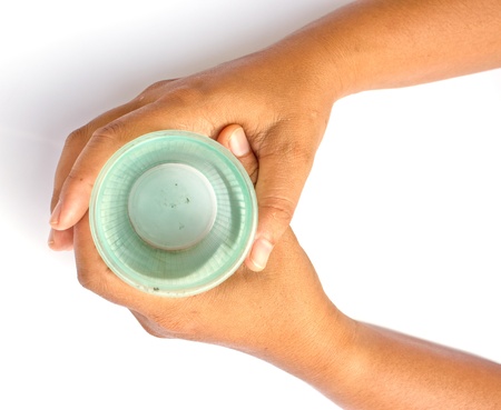 Hand holding a green plastic cup on a white background.