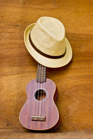 The ukulele and a hat is placed on a wooden floor.の写真素材