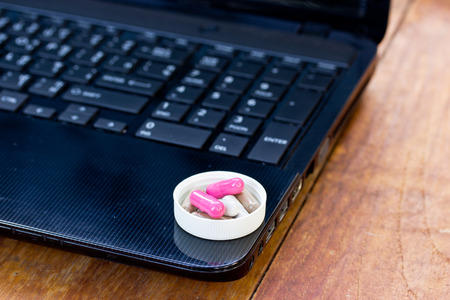 capsule and notebooks on wood table.The concept of hard work and had to take medicine.の写真素材