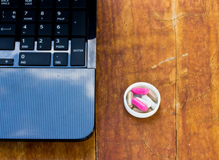 capsule and notebooks on wood table.The concept of hard work and had to take medicine.の写真素材