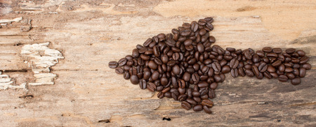 Arrow from the coffee beans on wood background
