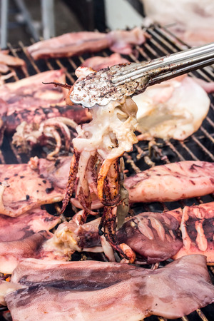 Close up fresh squid barbeque grilled on charcoal stoveの写真素材