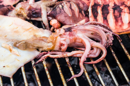 Close up fresh squid barbeque grilled on charcoal stoveの写真素材
