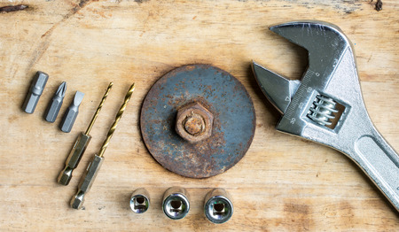 Pliers Drill, screwdriver and nut on a wooden floor.