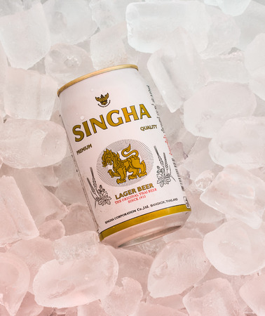 Chiang Rai, Thailand - April 14, 2015: Cans of Singha beer produced by Ale Brewery Co Ltd pictured on ice. The beer is allowed to display the Royal Garuda on the brand.のeditorial素材
