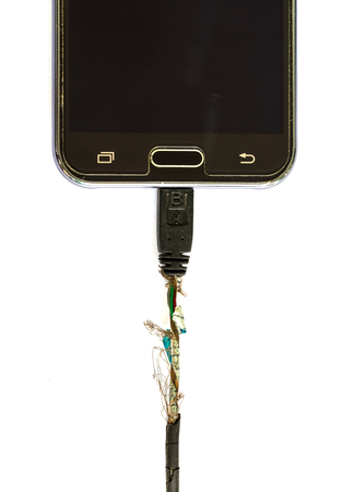 Damaged Charging of mobile phone on white background.The concept of the dangers of defective...