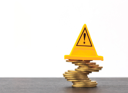 Risky coin stack and Warning label on white background.Financial crisis concept.の写真素材
