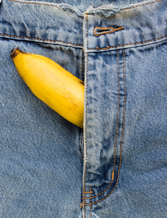 big banana sticks out of mens jeans like mens penis as potency conceptの写真素材