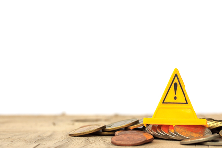 Financial risk. Coins falling and Warning label on whitebackgroundの写真素材