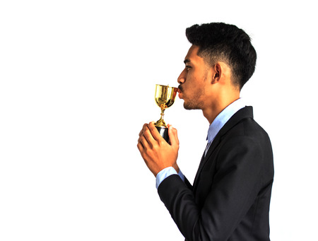 Businessman kissing a trophy because she has won the competitionの写真素材