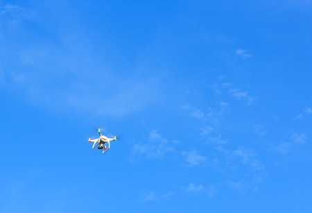 Flying drone with blue sky background controlled by professional photographer