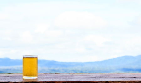 Beer in glass on wooden table with natural background with mountainの写真素材