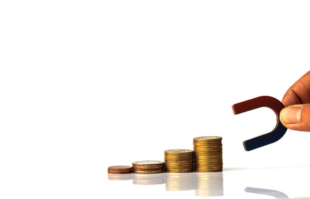 Horseshoe magnet with stack coins on white backgroundの写真素材