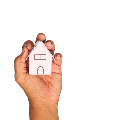 Pink paper house in human hands on a white background.の写真素材