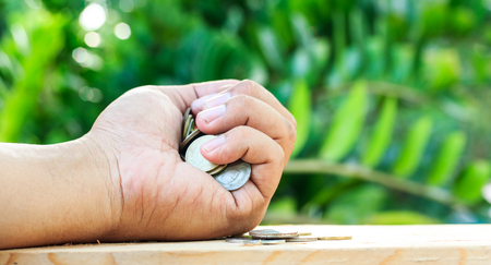 Holding many coins in the hand on the floor. Save money and use it for investment for your future.の写真素材