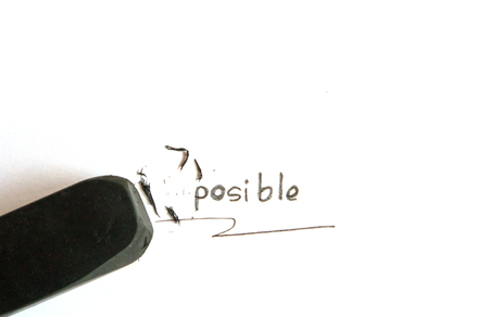 Black eraser on white paper erase letters IM from the word IMPOSSIBLE into POSSIBLE