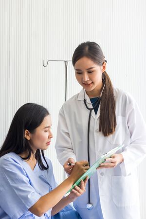 Patient listening intently to a male doctor explaining patient symptoms or asking a question as they discuss paperwork together in a consultationの写真素材