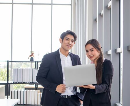 Young Asian businessmen and business women consult the work together. By looking at the notebook in the workplaceの写真素材