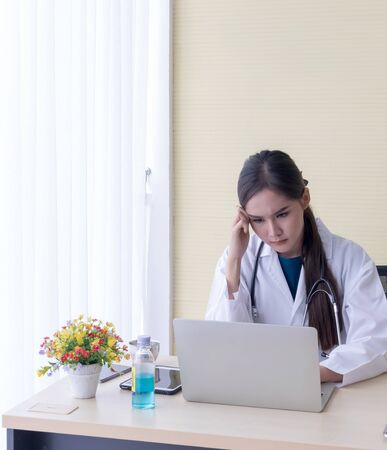Asian female doctor watched A headache job in a notebookの写真素材