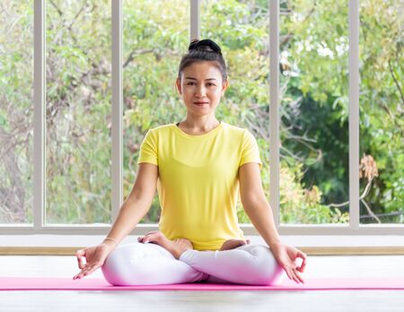 An Asian female yoga teacher wearing a yellow shirt is training her body to be strong and healthy with yoga.の写真素材