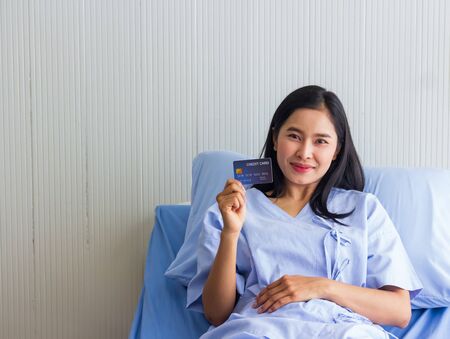 Young Asian female patient holding credit card and smiling.の写真素材
